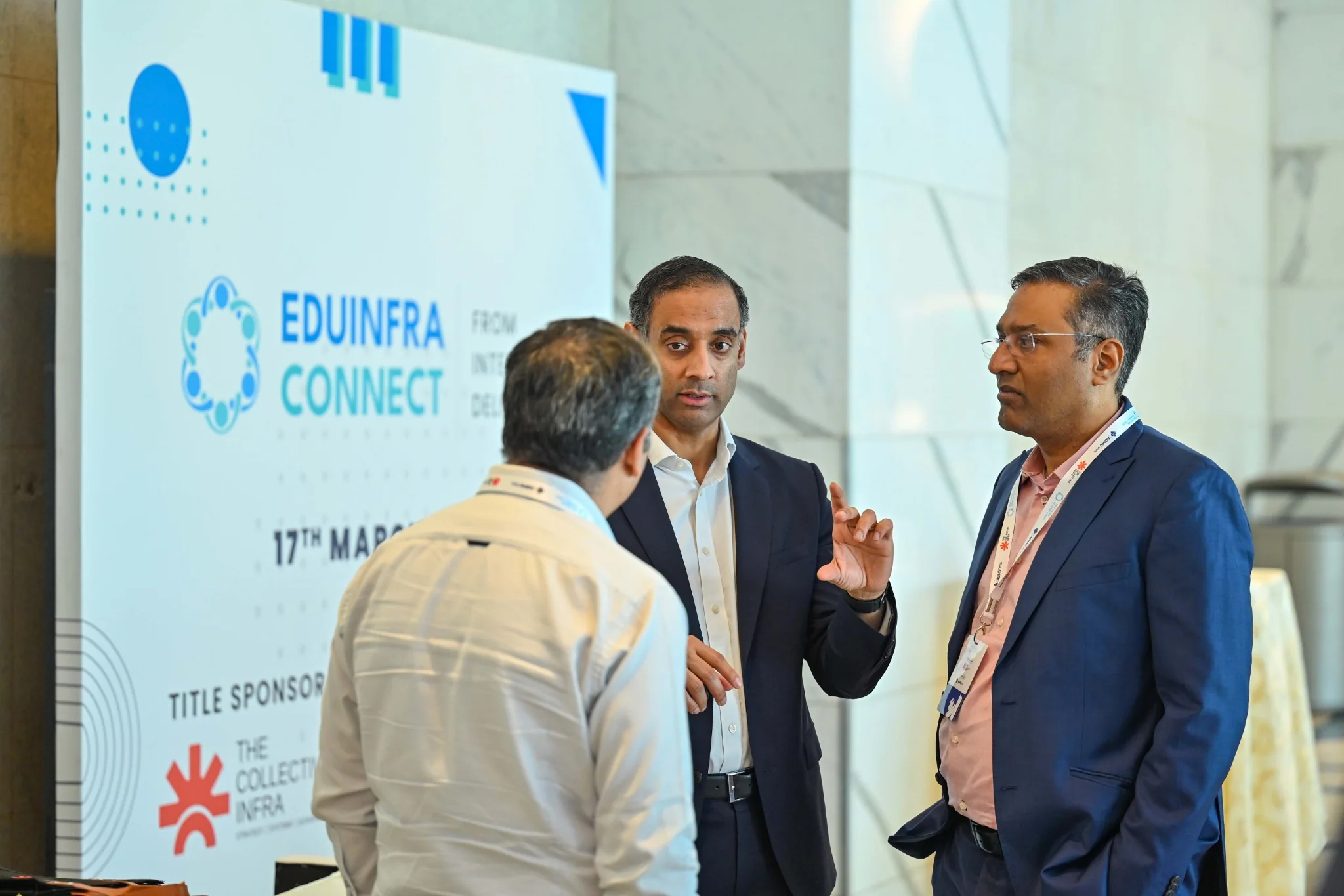EduInfra Connect participants discussing an infrastructure opportunity beside event branding